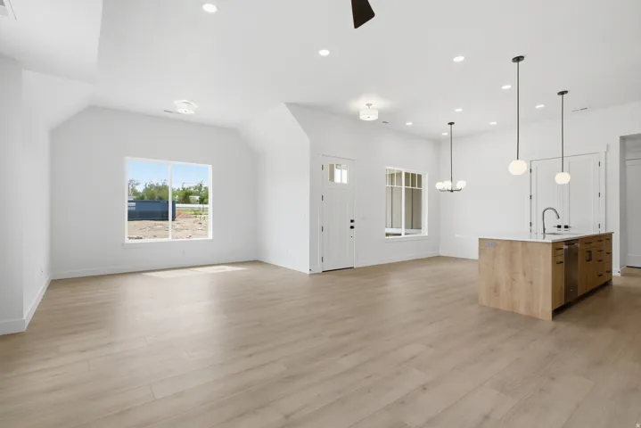 Kitchen with open floor plan, a kitchen island with sink, suspended lighting, and light wood-type flooring