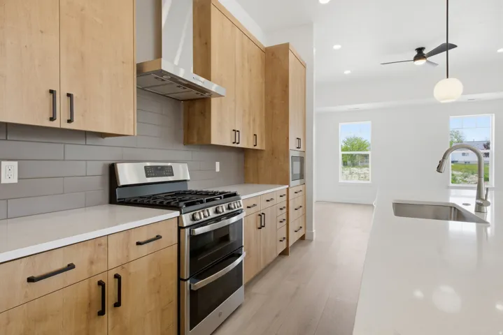 Kitchen featuring light wood finish cabinetry, stainless steel appliances, hanging light fixtures, and light wood-style flooring