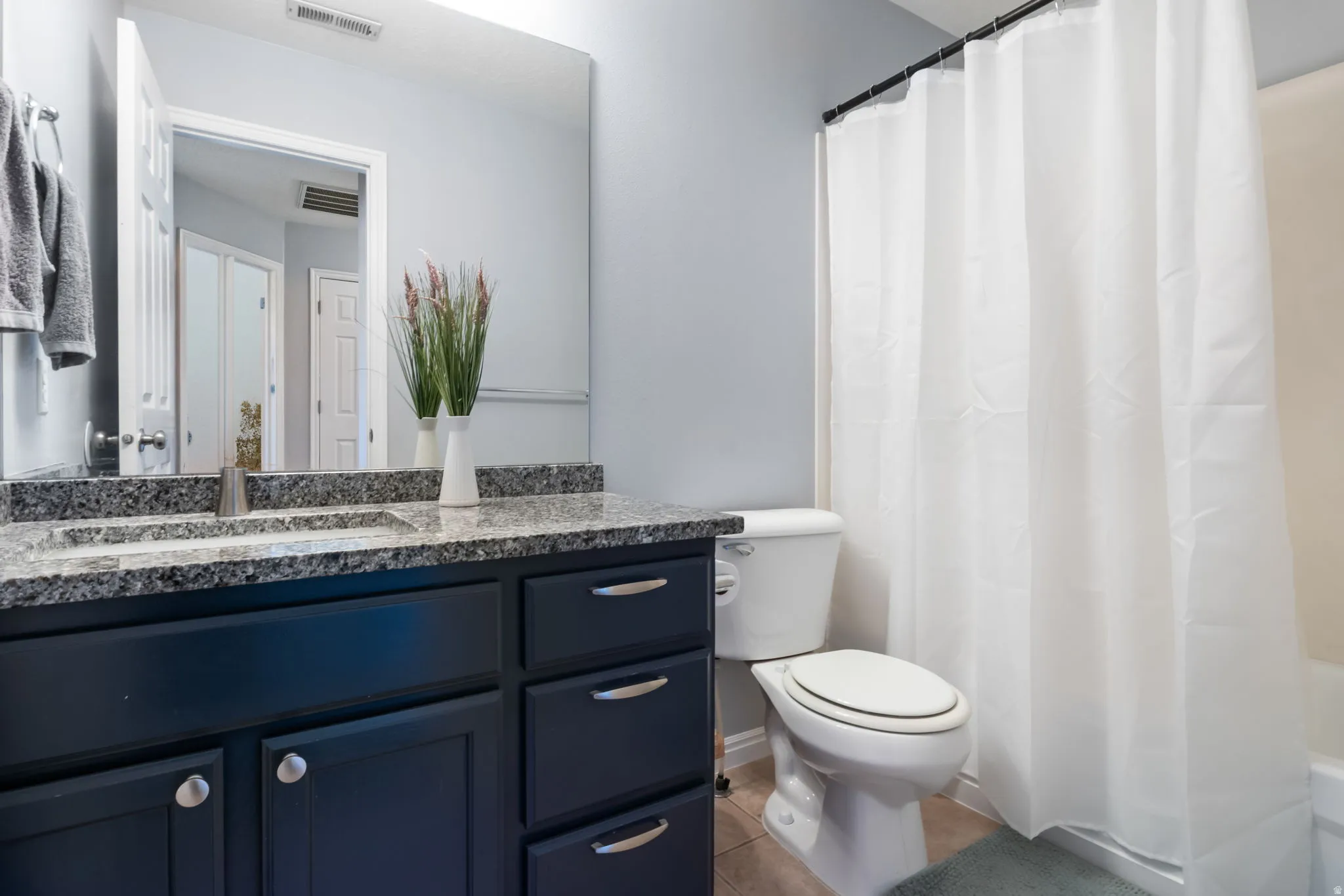 Bathroom with vanity, light tile patterned floors, and shower / bathtub combination with curtain
