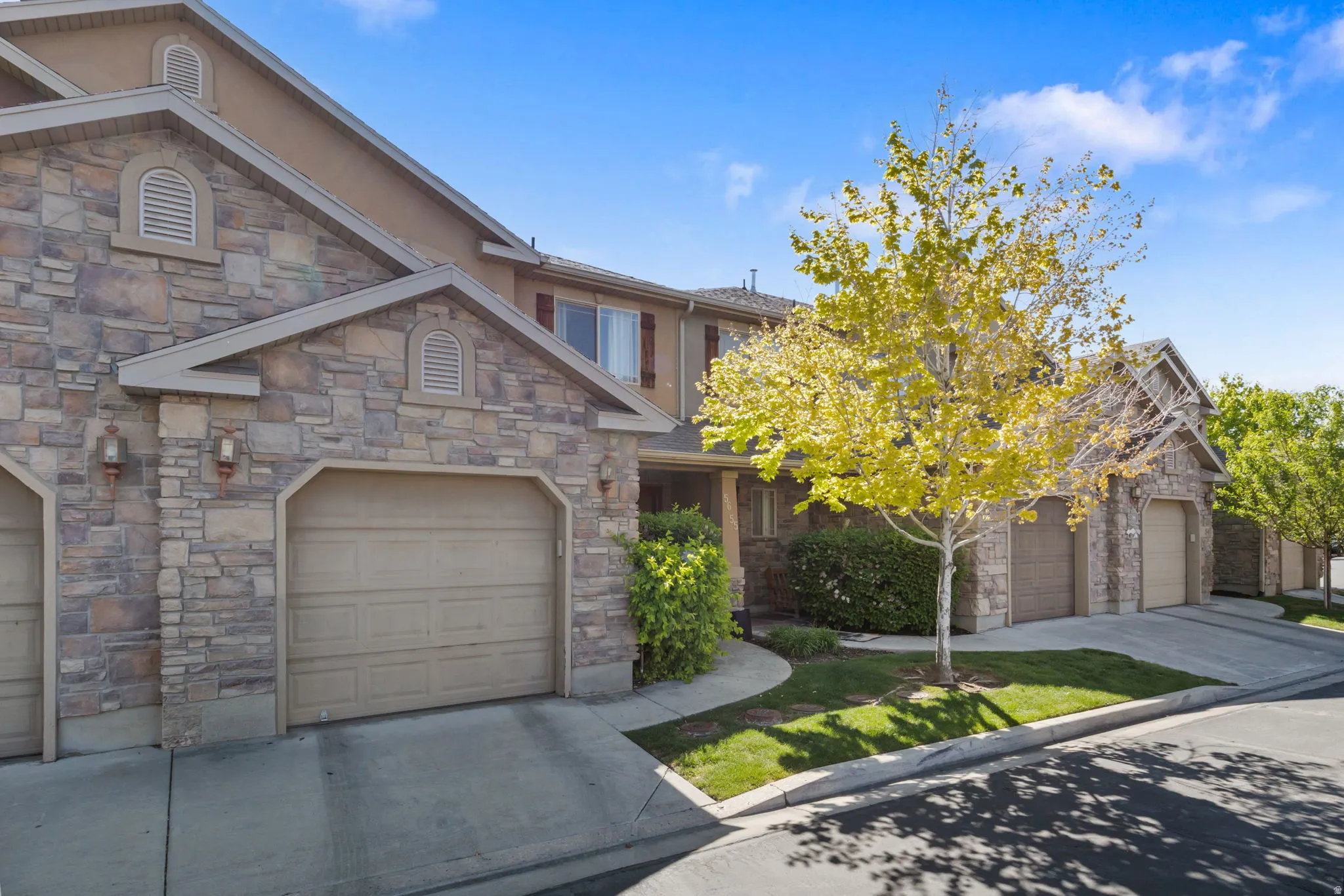 Craftsman inspired home featuring stone siding, a garage, and concrete driveway