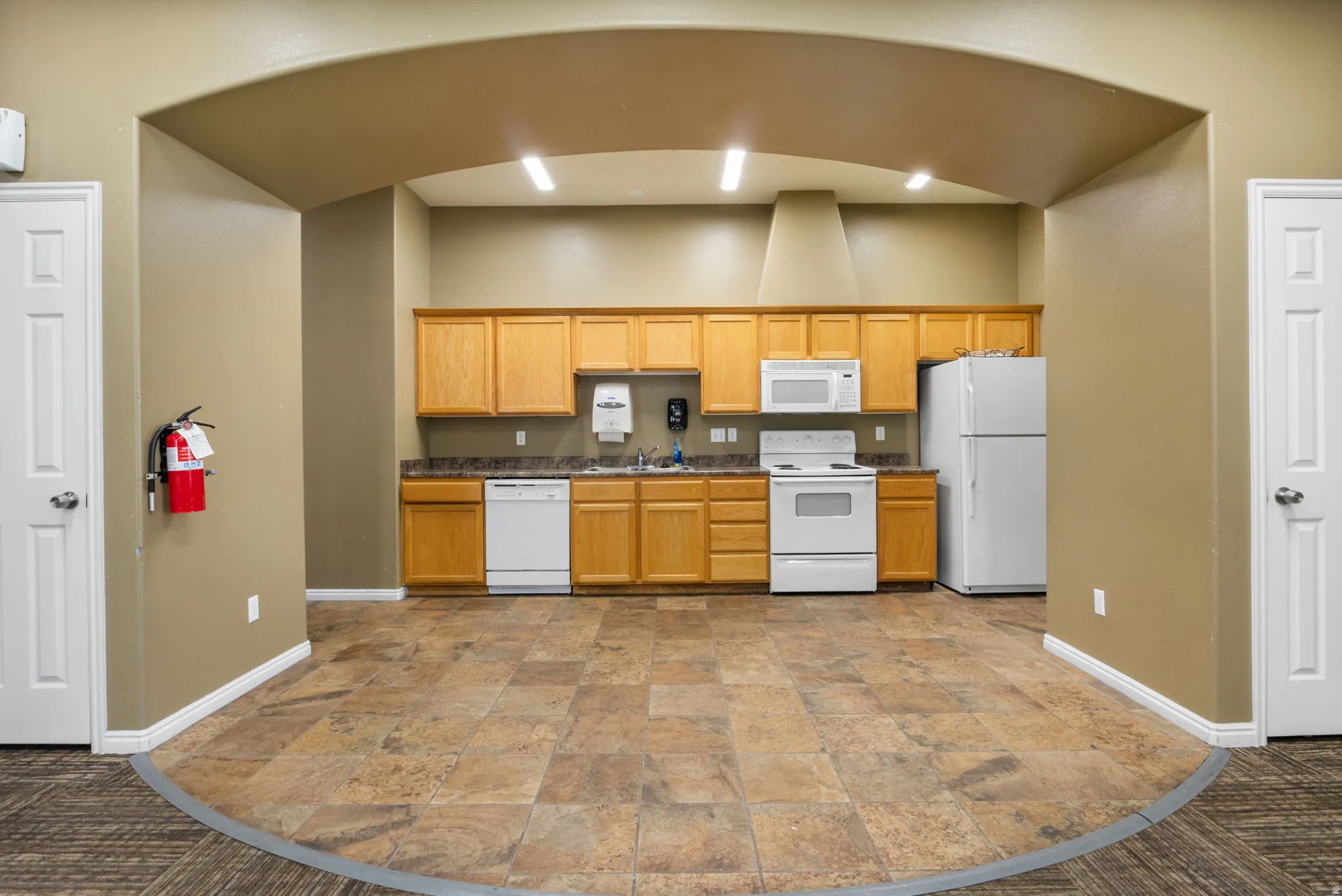 Kitchen featuring white appliances, stone finish floors, and dark carpet