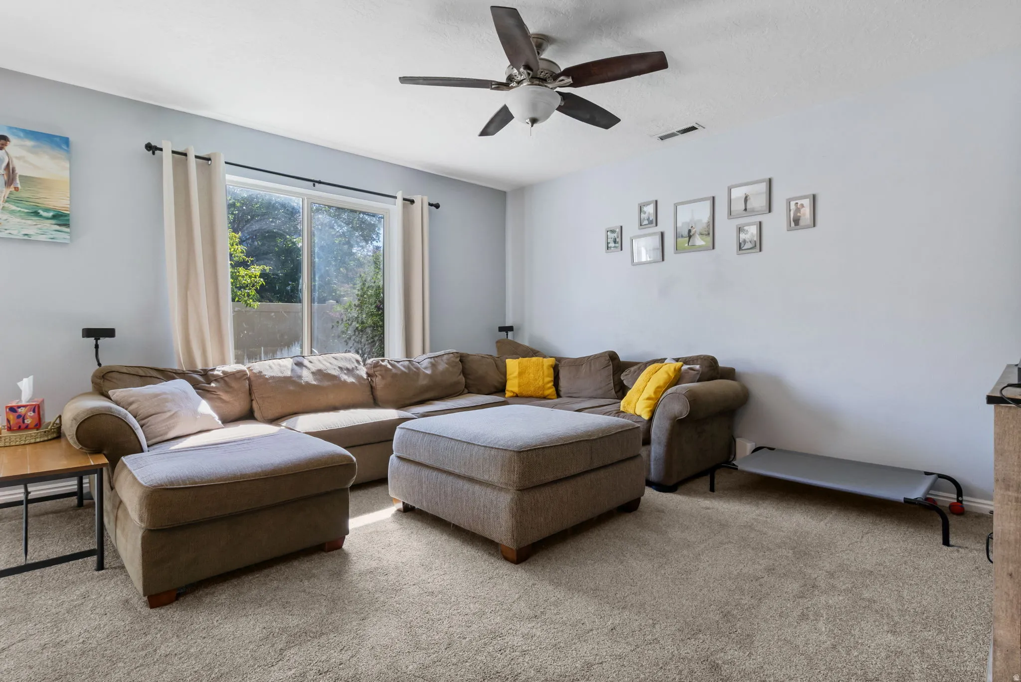 Carpeted living area featuring ceiling fan