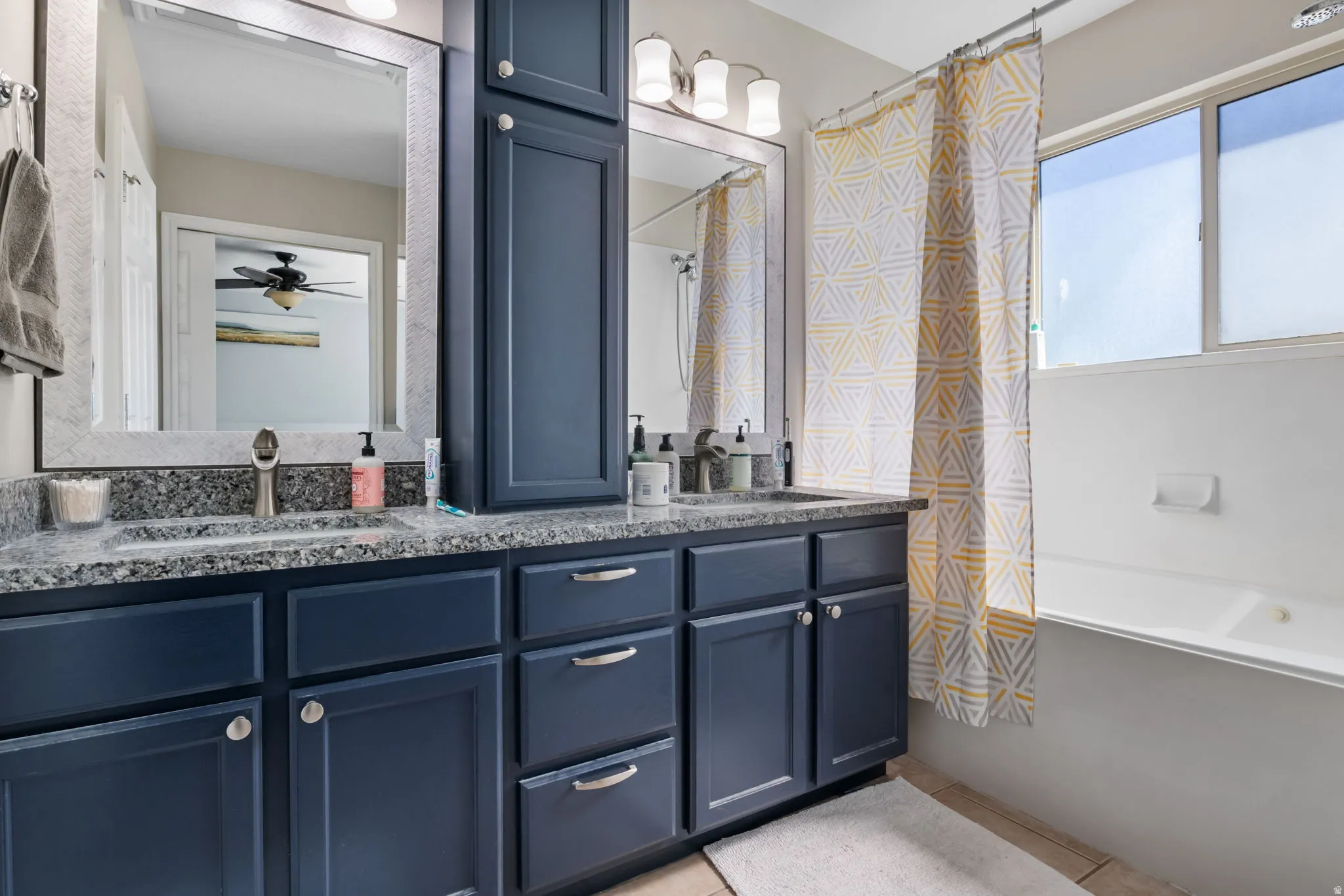Bathroom featuring double vanity, shower / tub combo, and a ceiling fan
