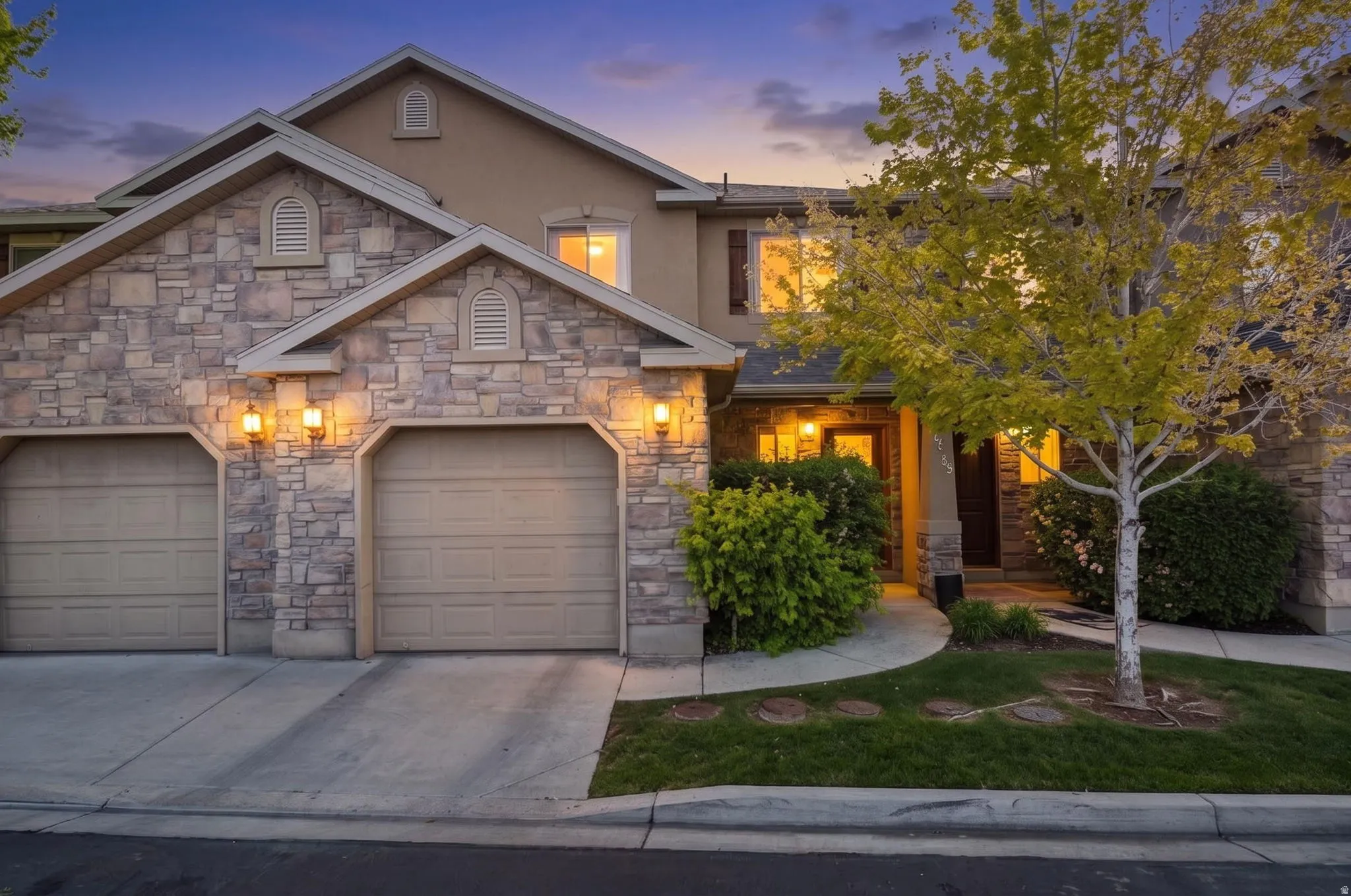 View of front facade with concrete driveway, stone siding, stucco siding, and a garage