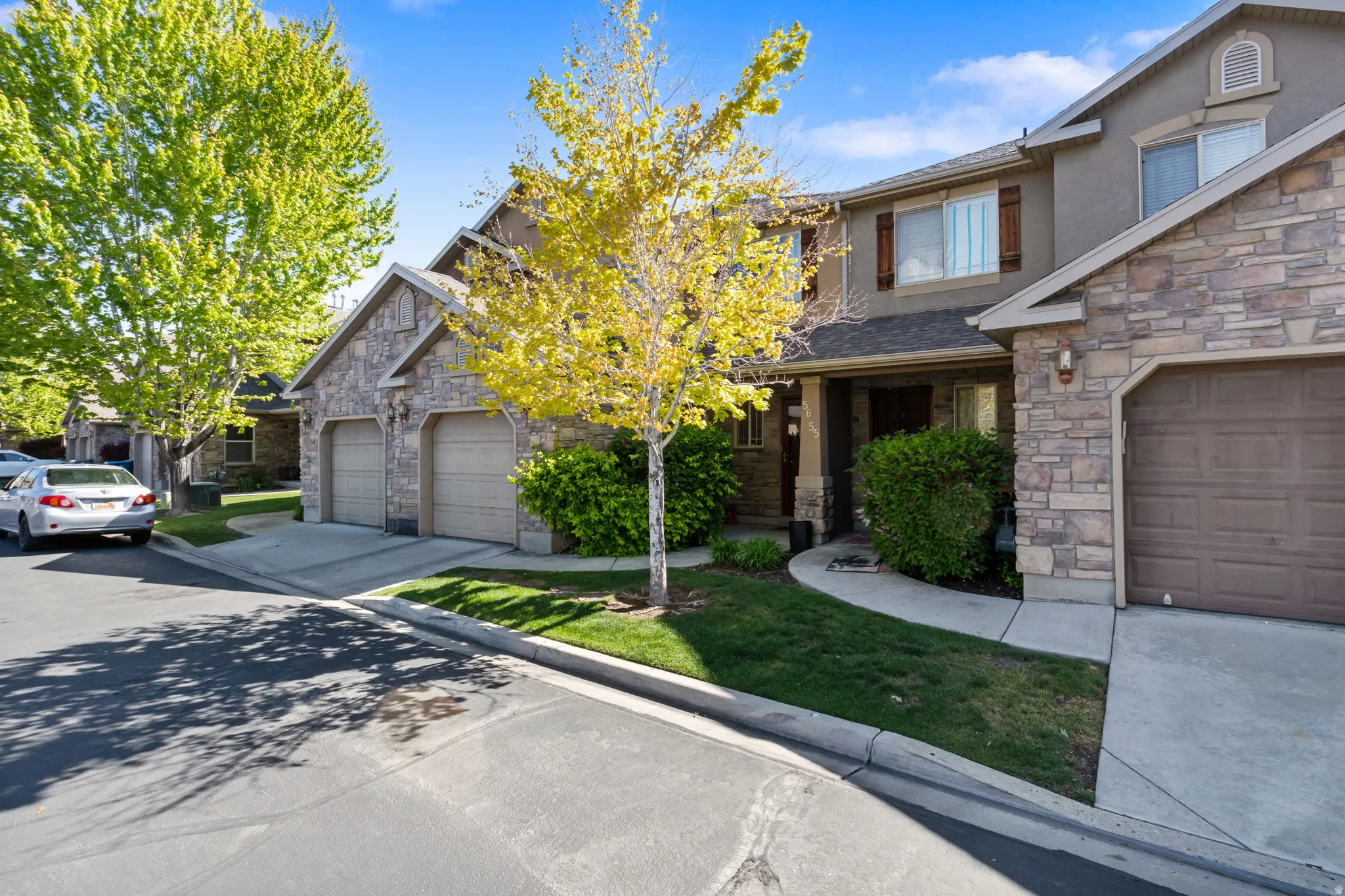 View of front of house with stone siding, stucco siding, driveway, and an attached garage