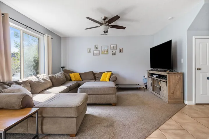 Living room with light carpet, a ceiling fan, and light tile patterned floors