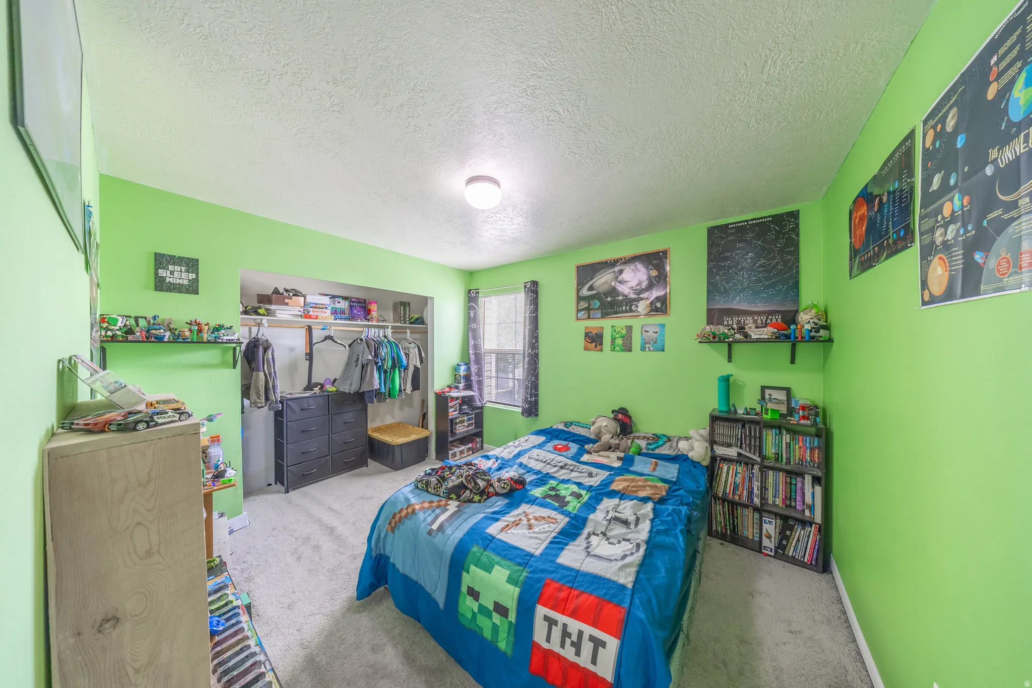 Carpeted bedroom featuring a textured ceiling and a closet