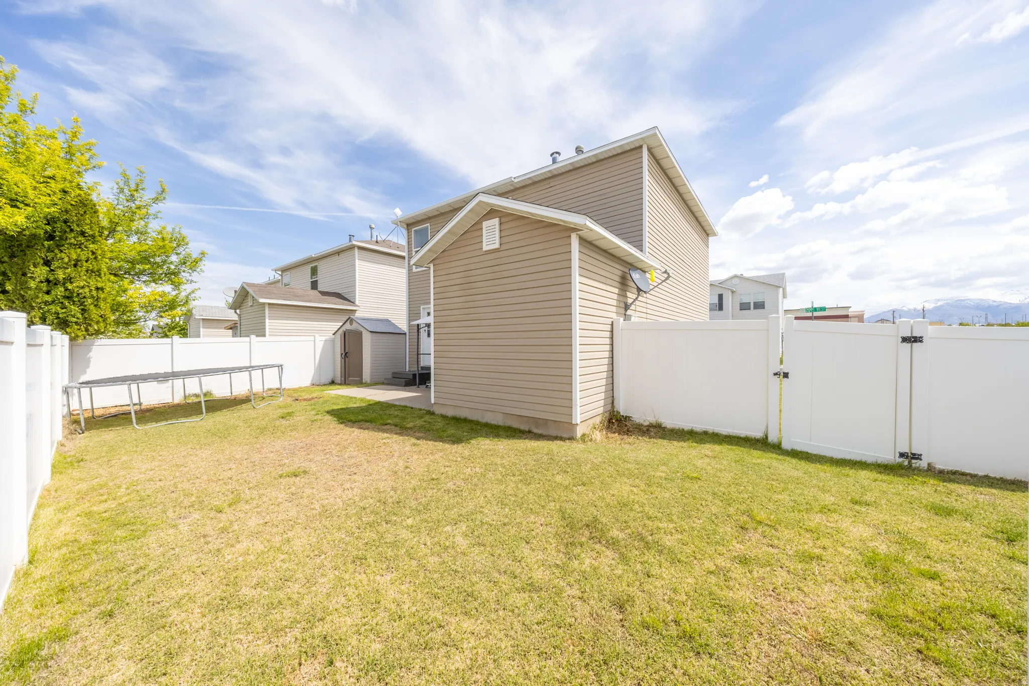 Back of house featuring a gate, a fenced backyard, and a storage shed