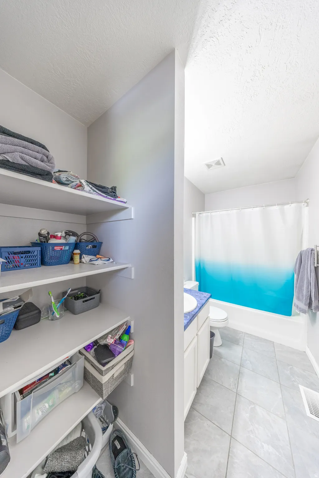 Full bathroom with vanity, shower / bath combo with shower curtain, and a textured ceiling