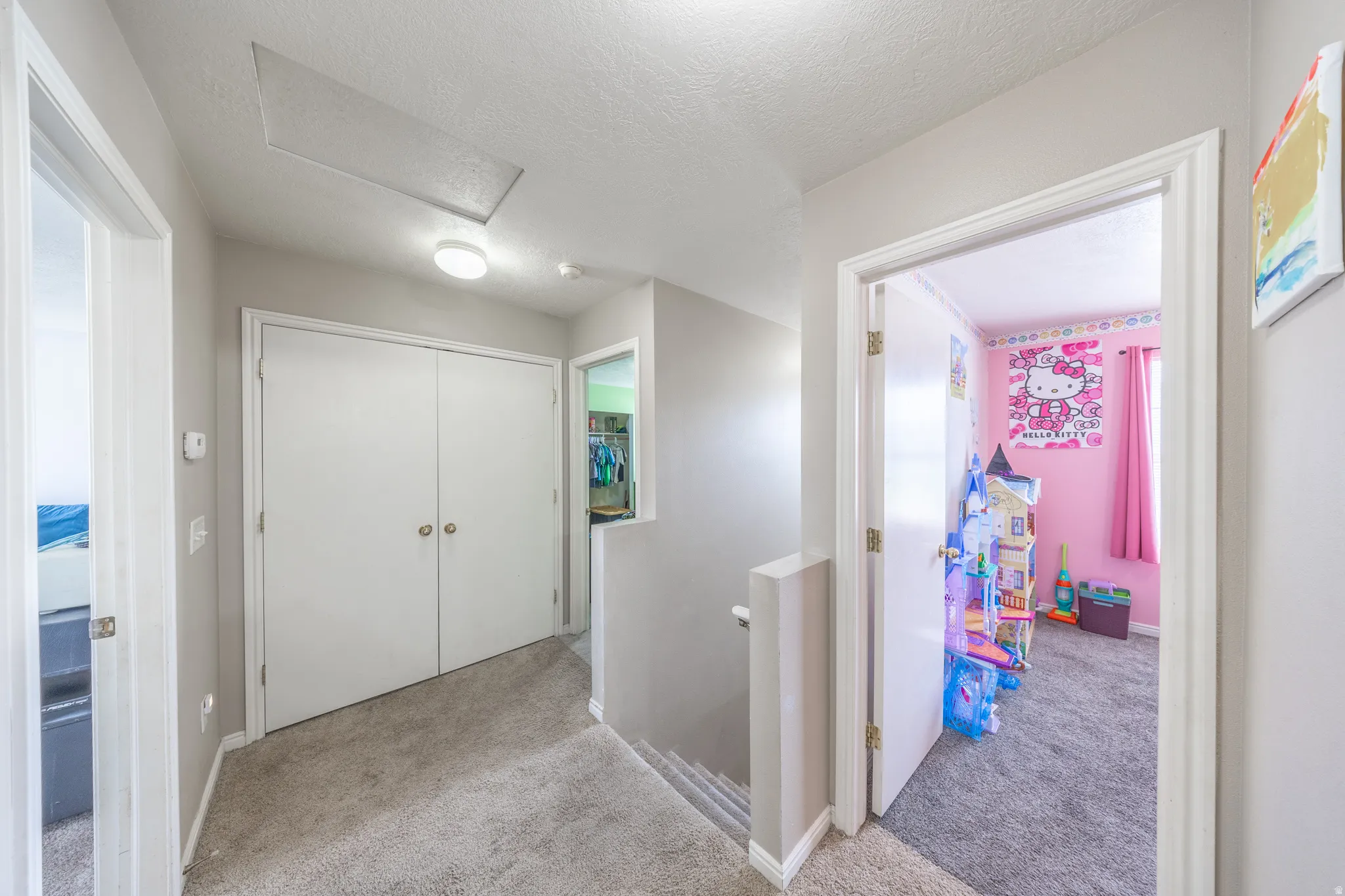 Corridor featuring an upstairs landing, light carpet, and a textured ceiling