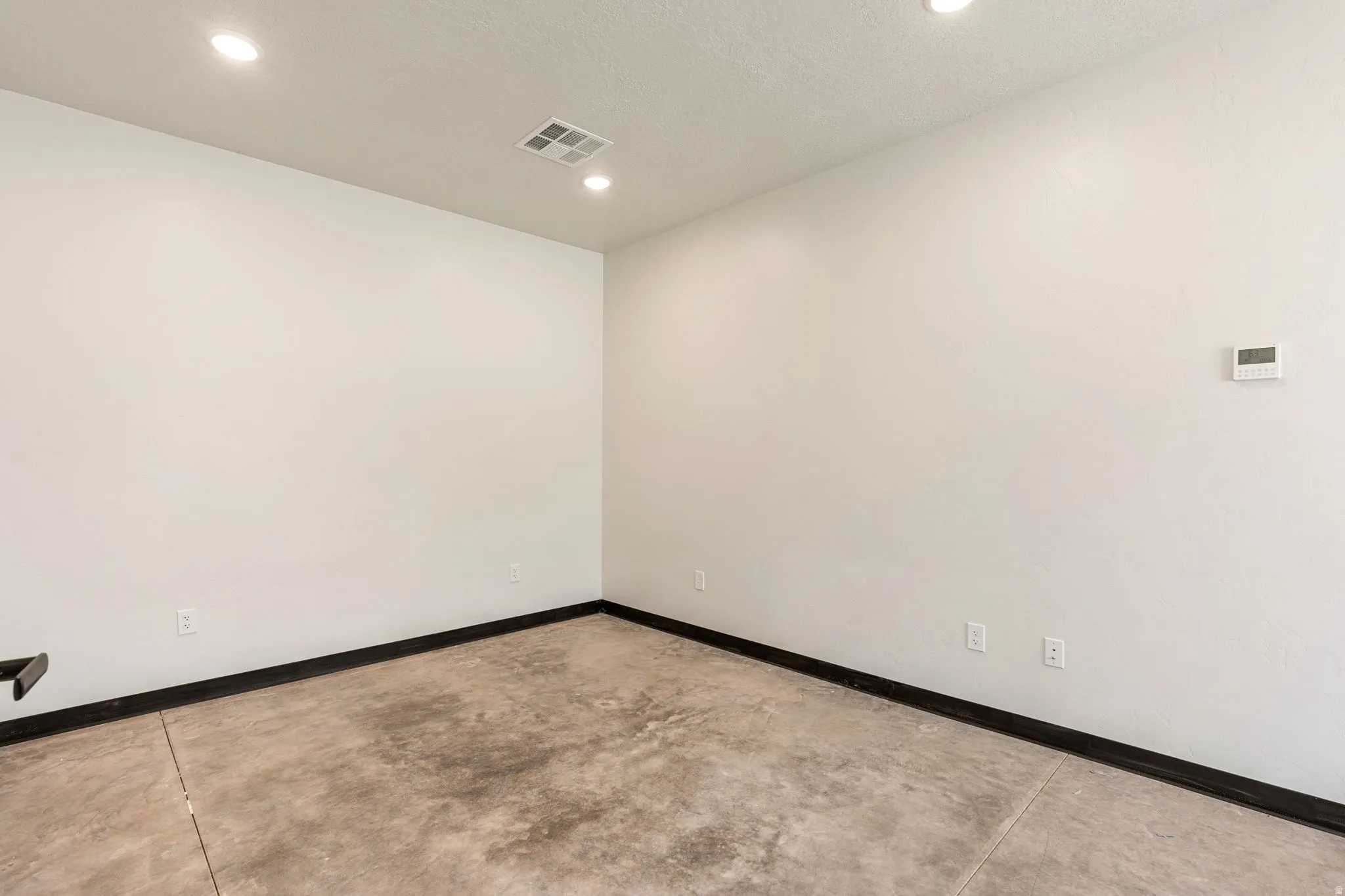 Empty room featuring concrete floors and recessed lighting
