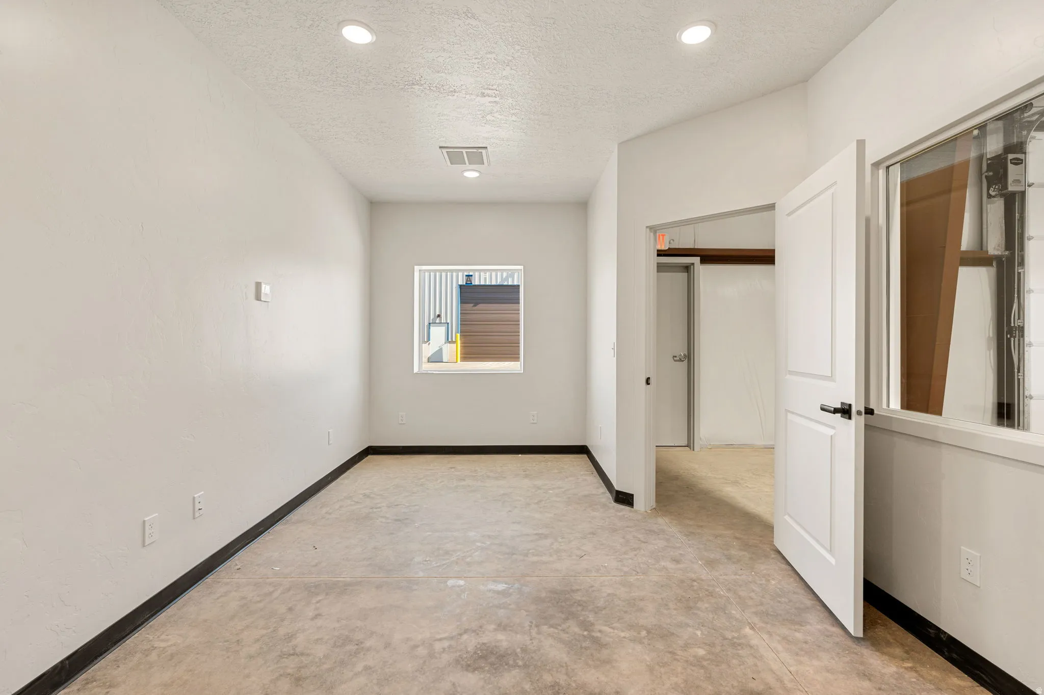 Hall with a textured ceiling, concrete floors, and recessed lighting
