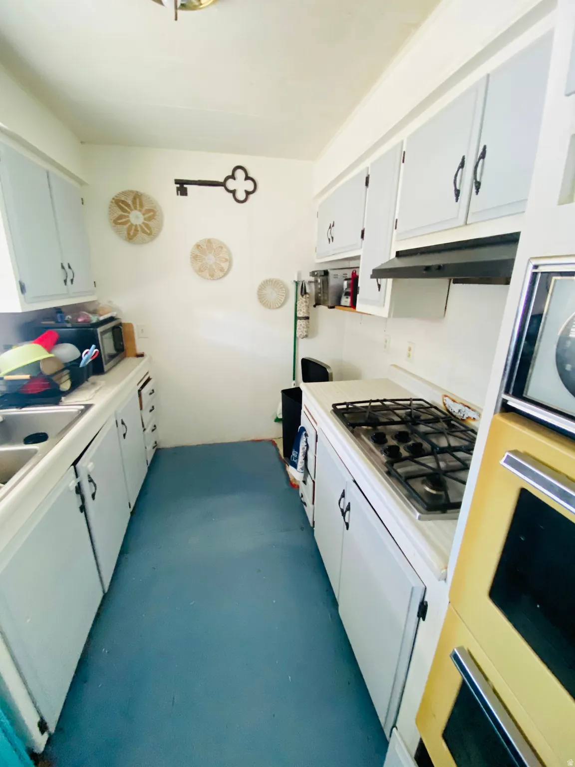Kitchen featuring light countertops, gas cooktop, white cabinets, and oven