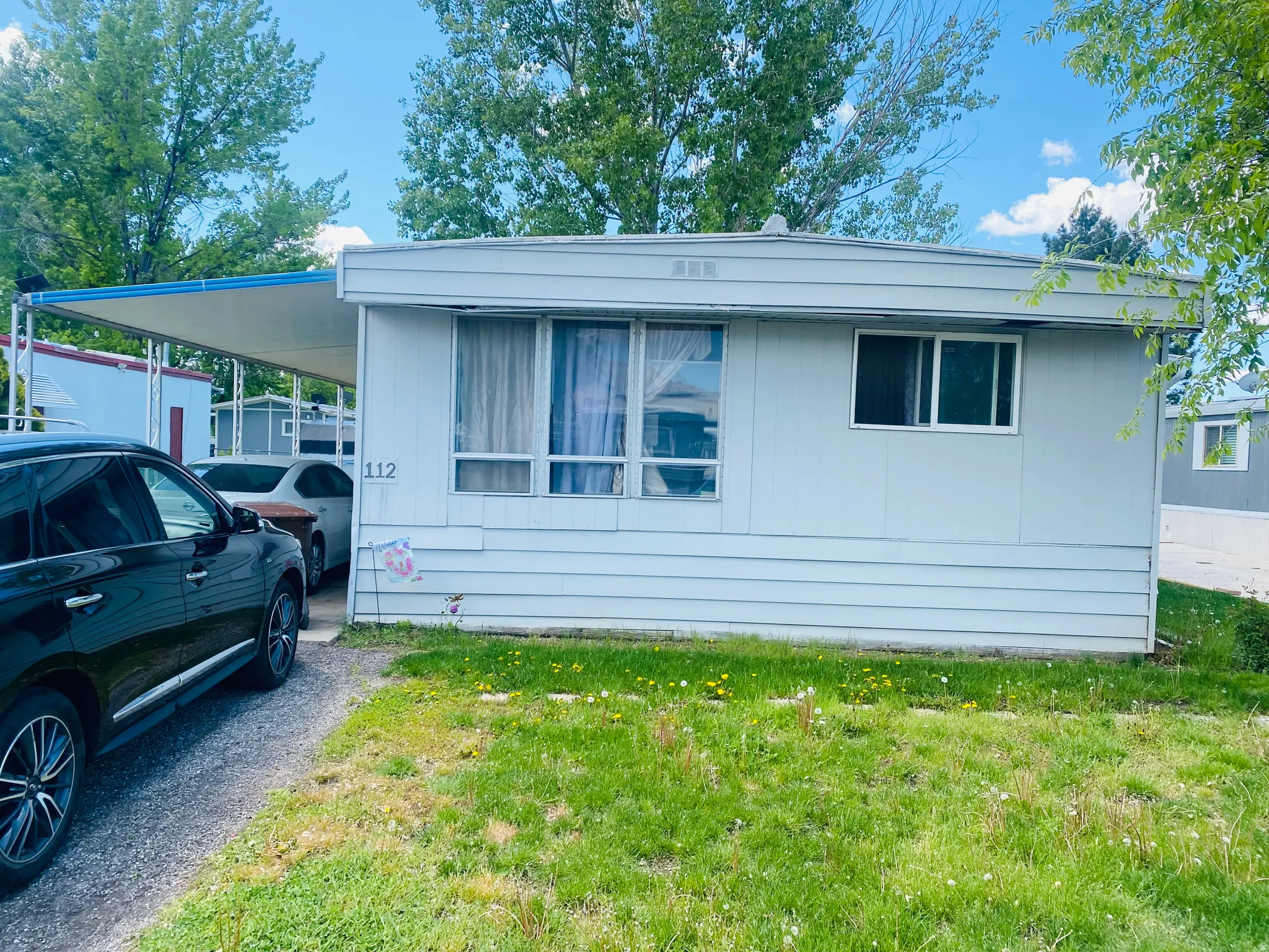 View of property exterior with a lawn and an attached carport