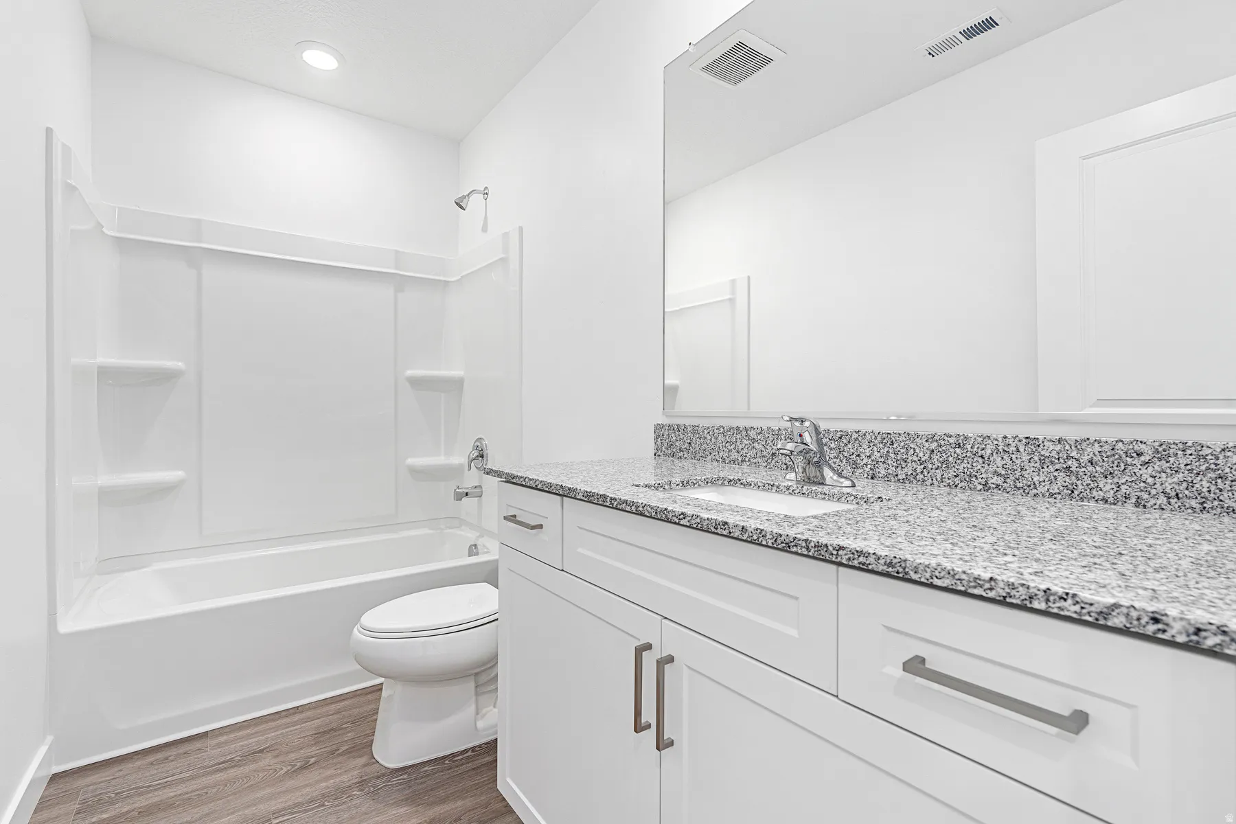 Bathroom featuring vanity, dark wood-type flooring, and shower / washtub combination