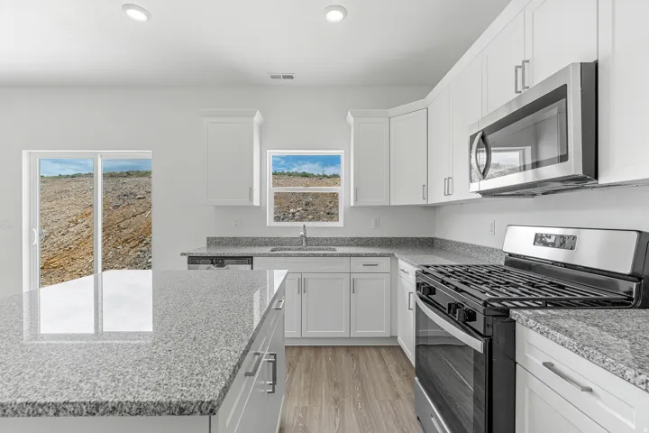 Kitchen featuring stainless steel appliances, white cabinetry, light stone countertops, light wood-type flooring, and recessed lighting