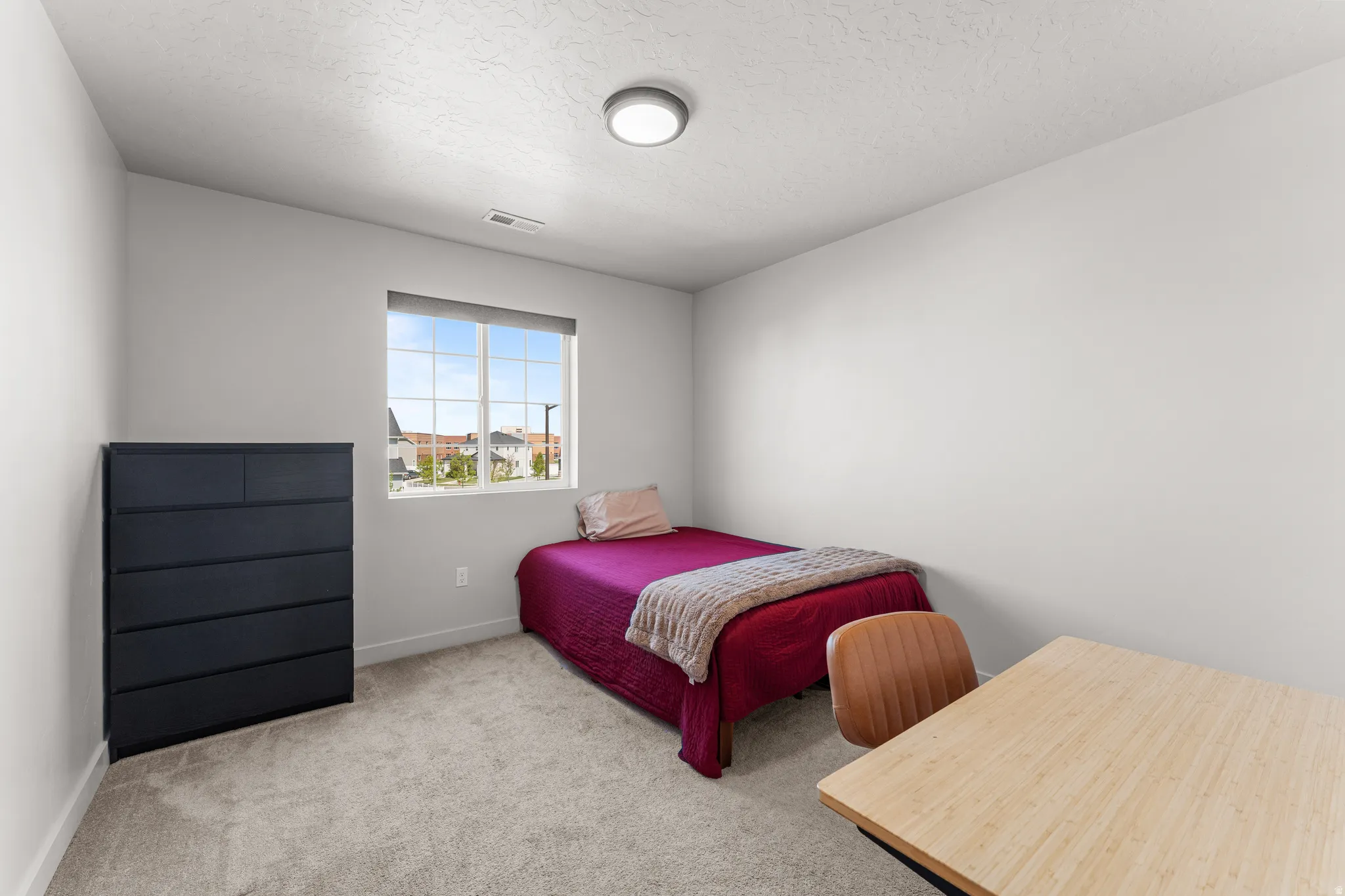 Bedroom with light carpet and a textured ceiling