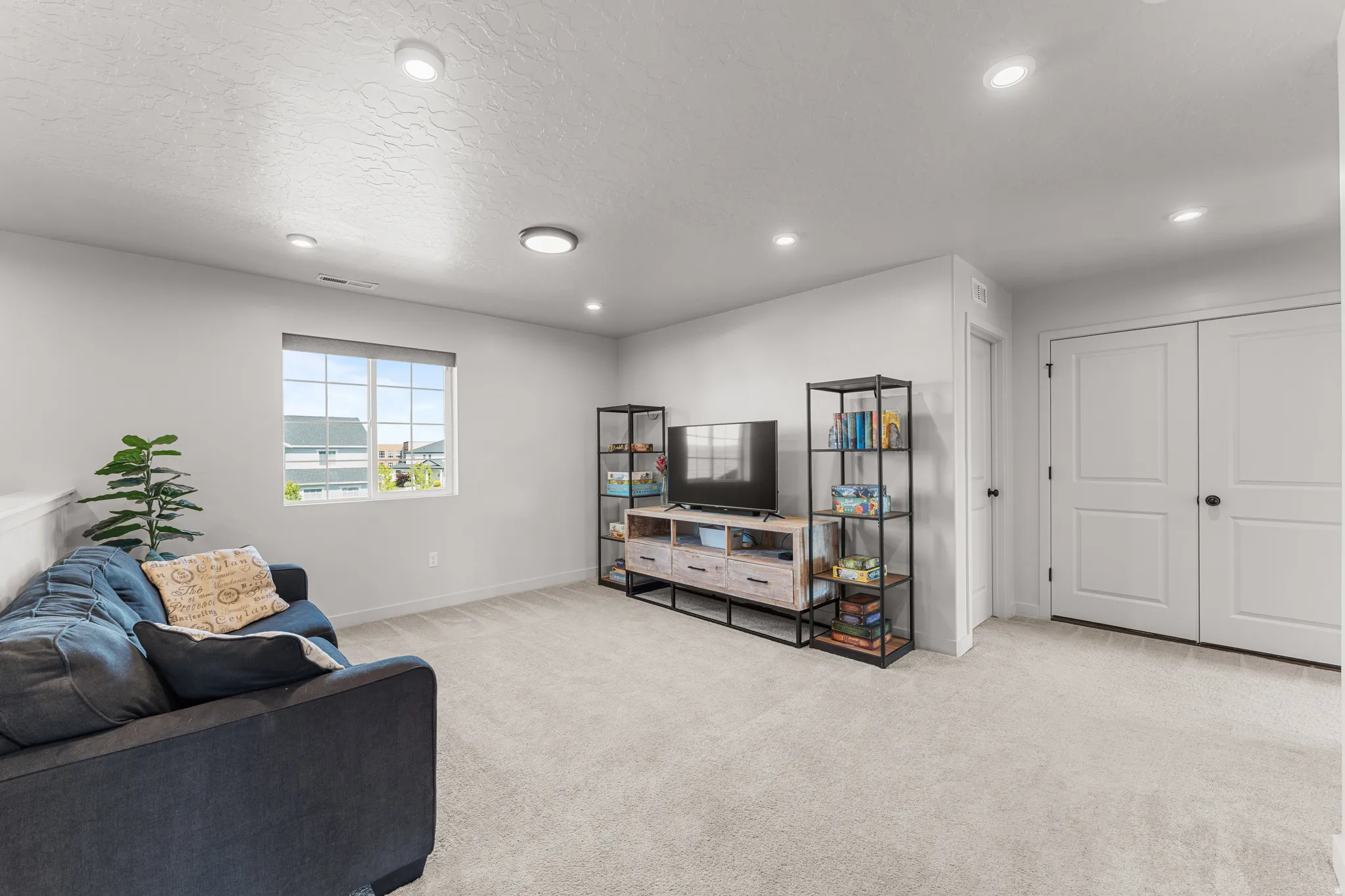 Living area with light carpet, recessed lighting, and a textured ceiling