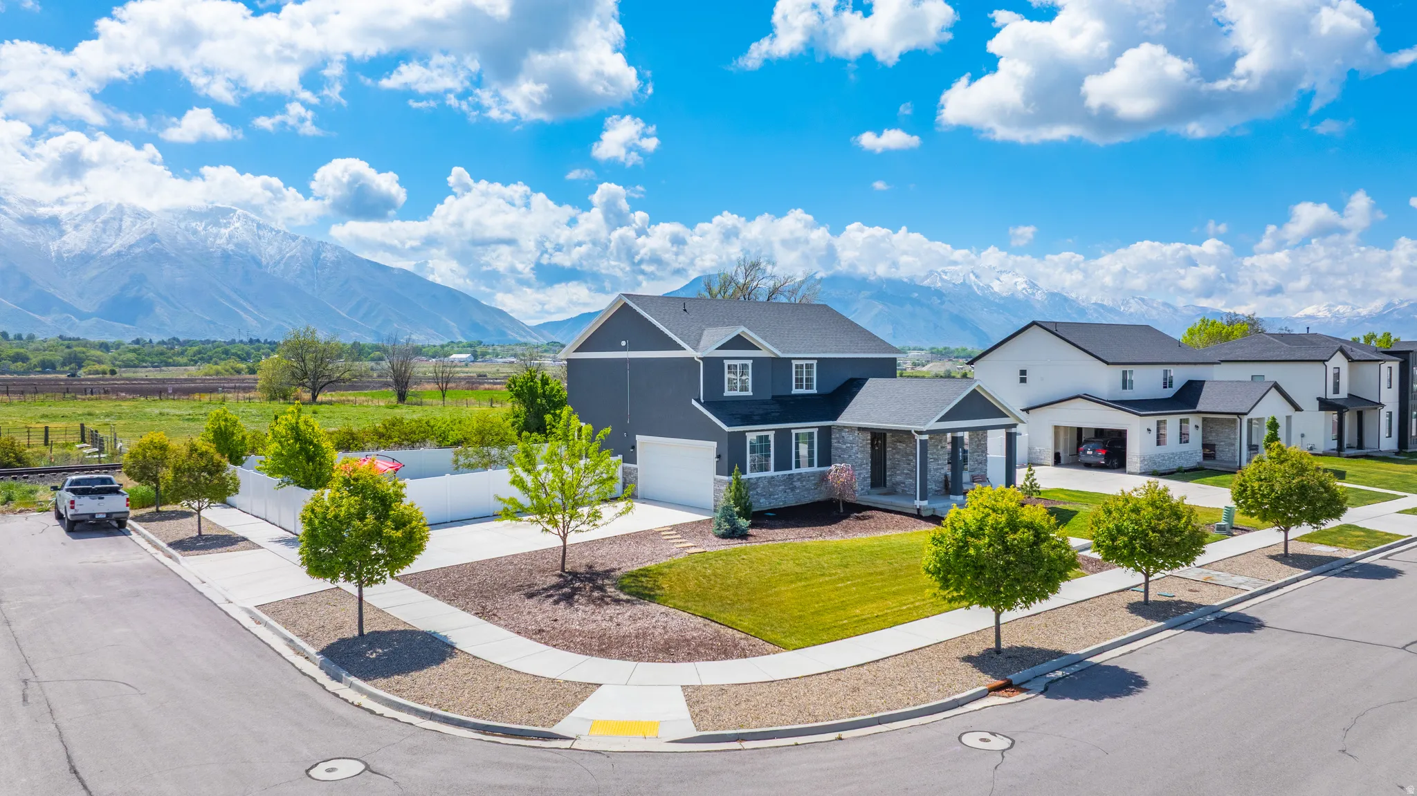 Traditional home with a mountain view, driveway, a porch, stone siding, and a front lawn