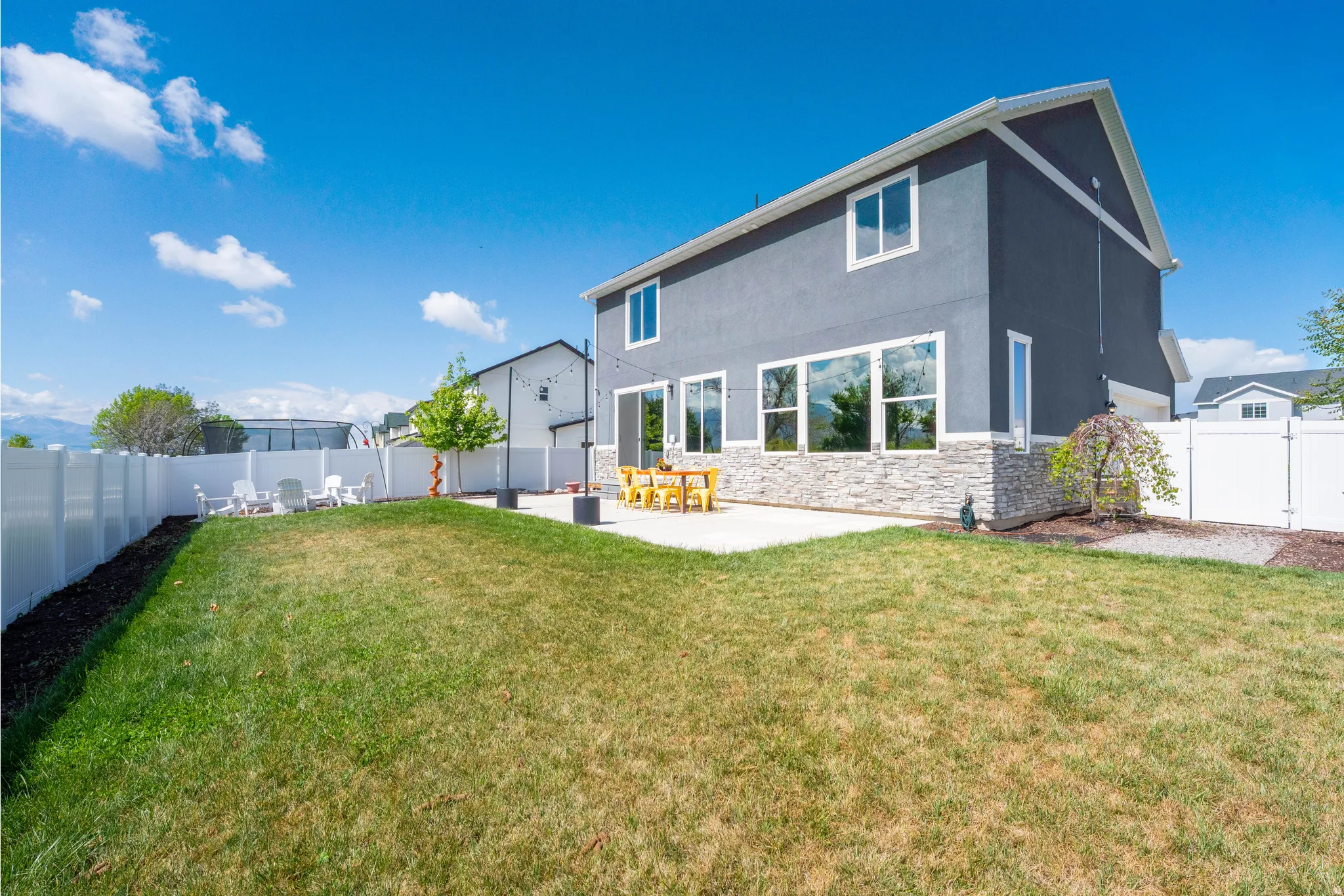 Rear view of house featuring a fenced backyard, stucco siding, a patio area, and stone siding