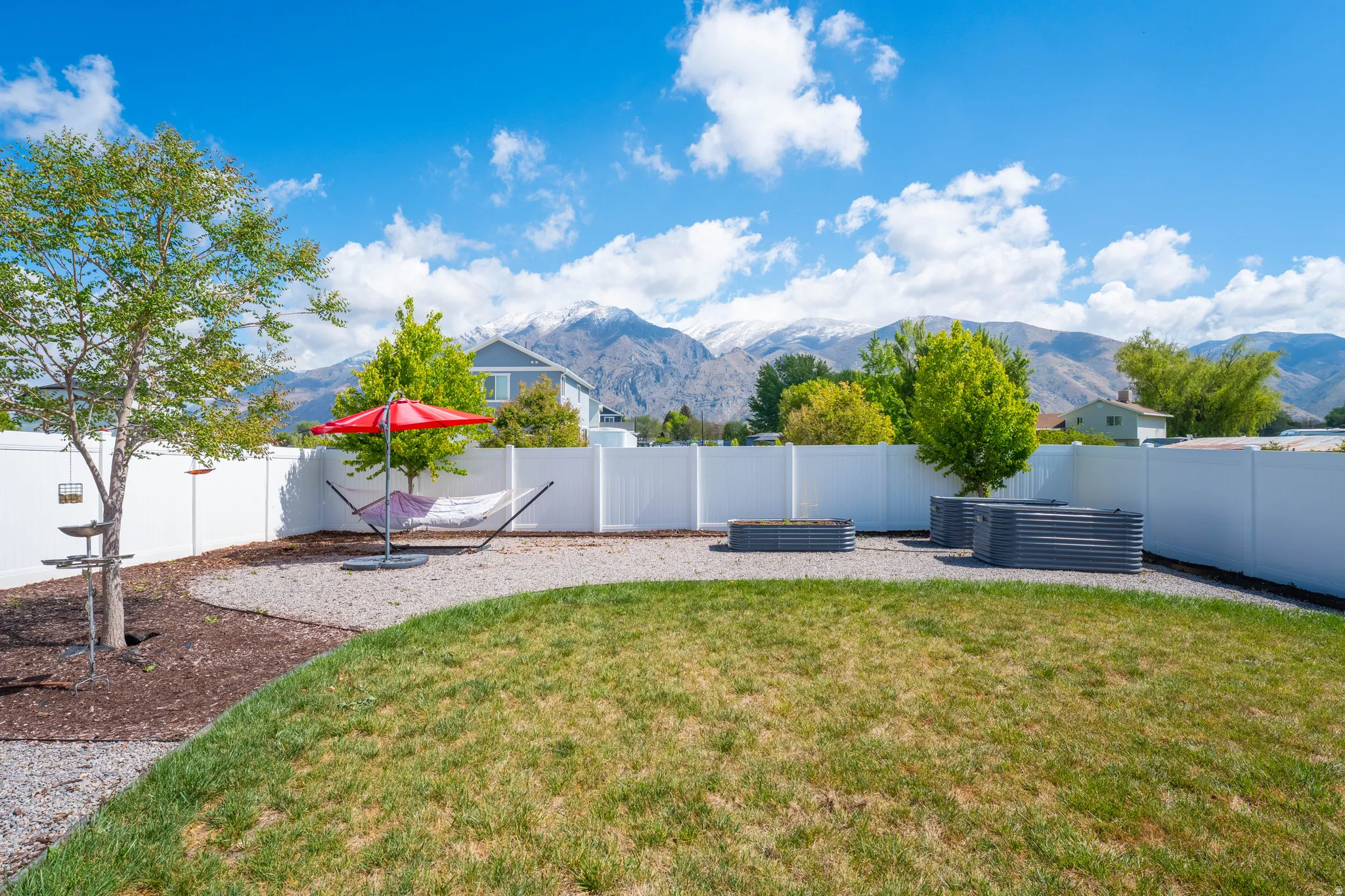 Fenced backyard featuring a mountain view and a vegetable garden