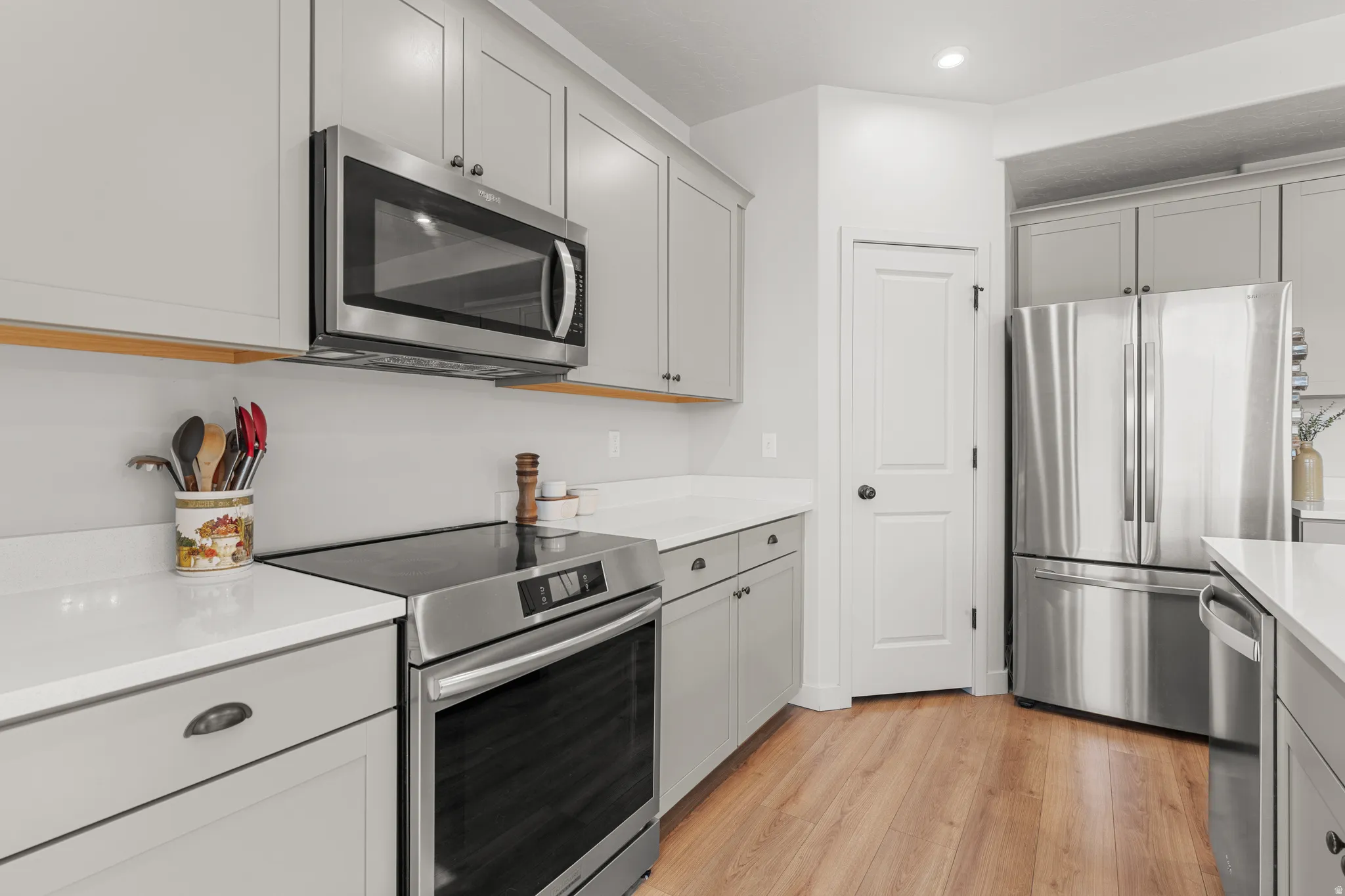 Kitchen featuring stainless steel appliances, light wood-style floors, light stone counters, gray cabinetry, and recessed lighting
