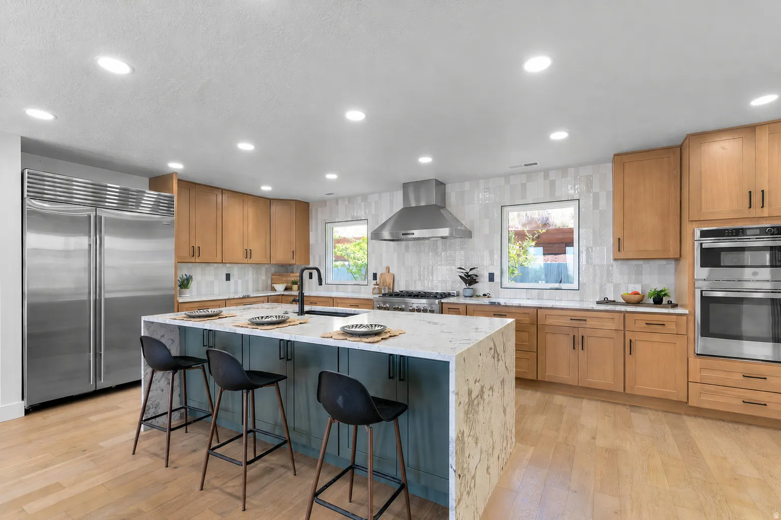 Spacious kitchen featuring a large island with a waterfall countertop, integrated sink, and seating for three