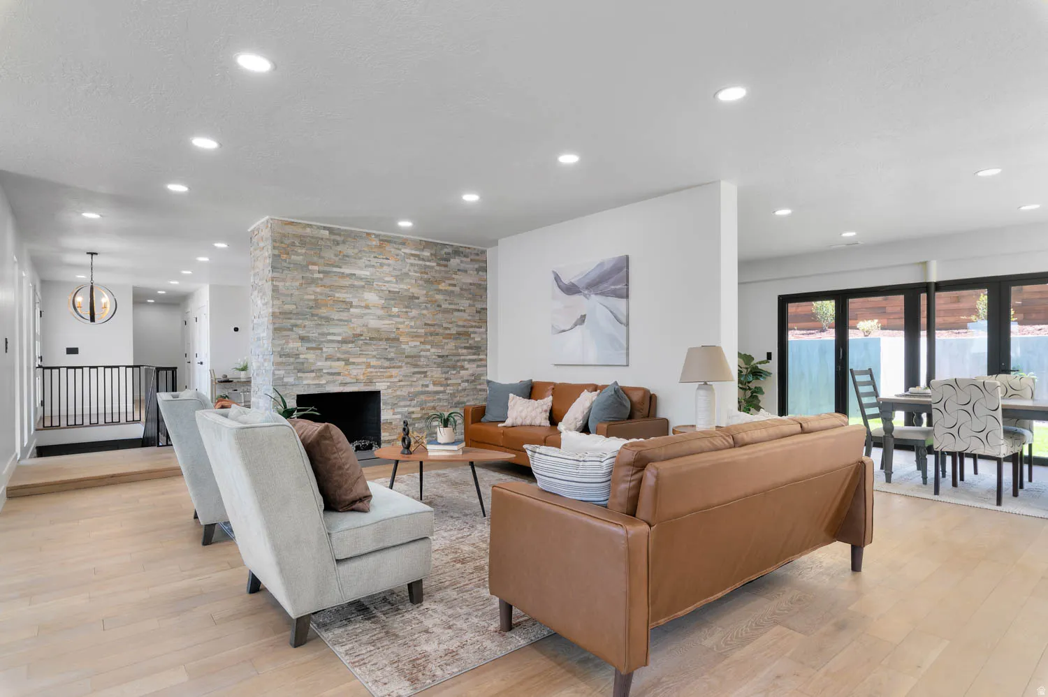 Living area featuring a stone accent wall with a fireplace, recessed lighting, and light wood-finish flooring