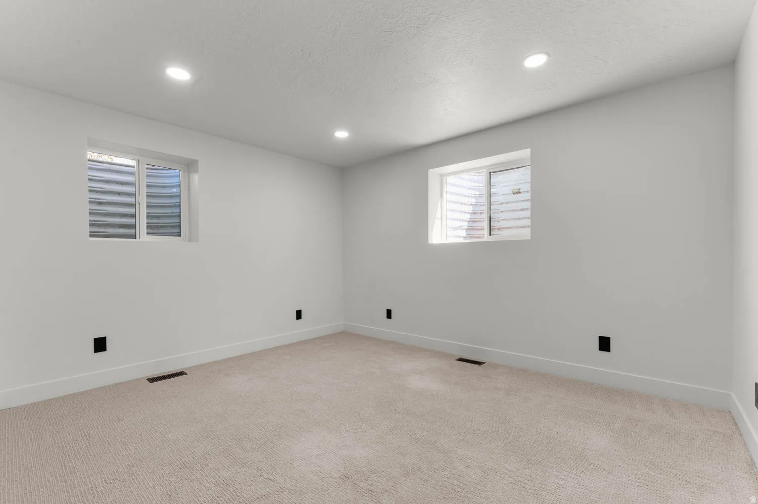 Spare room featuring light colored carpet, recessed lighting, and a textured ceiling
