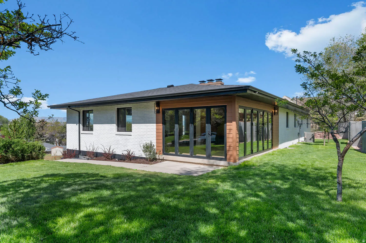 Back of property featuring brick siding, a lawn, and a sunroom