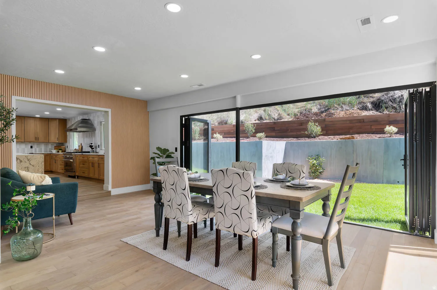 Dining area with wood-finish flooring, recessed lighting, and a bi-fold glass door system opening to an exterior grassy area