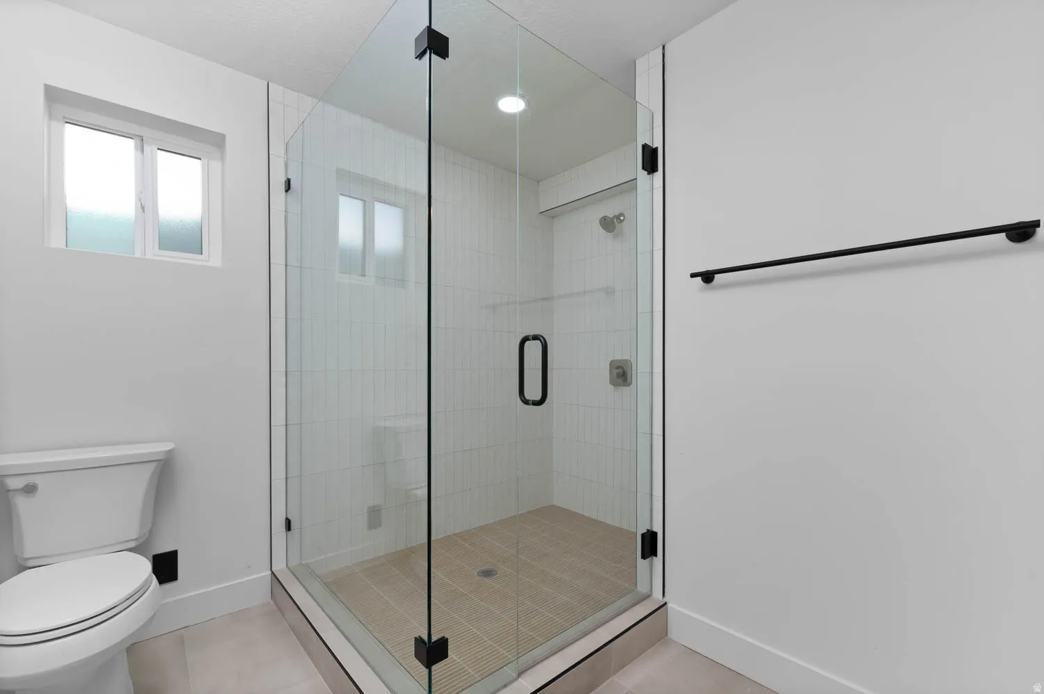 Glass-enclosed shower with subway tile surround and coordinating floor