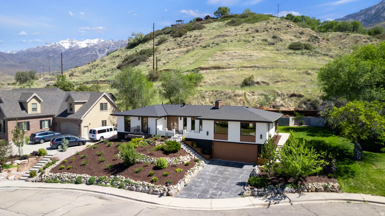 Contemporary-style residence featuring a dark-pitched roof, white and wood-paneled exterior, and a two-car garage