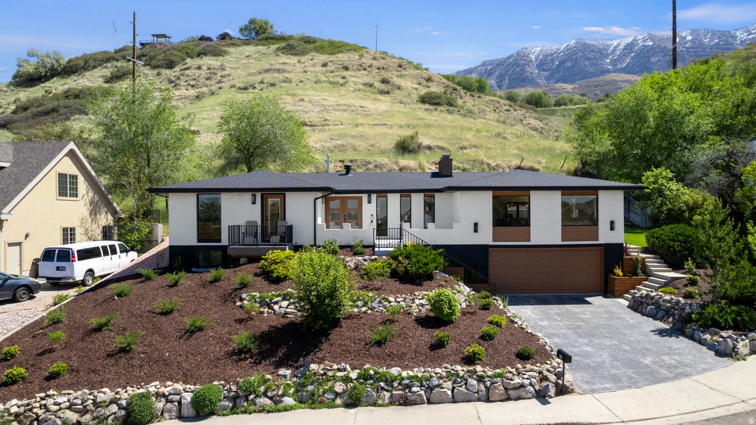 Modern single-story residence featuring a white and dark gray exterior with wood-tone accents