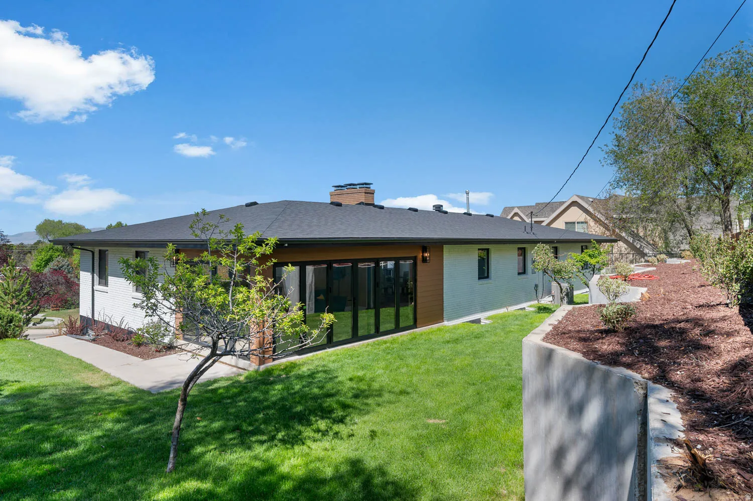 Back of property featuring a chimney, a lawn, and brick siding