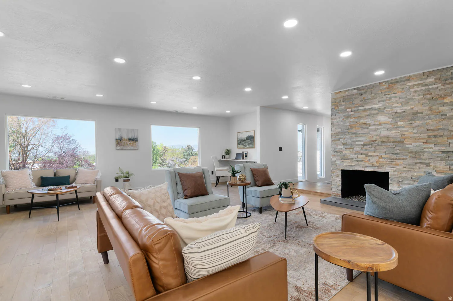 Spacious living area featuring a stacked stone fireplace, recessed lighting, and wood-finish flooring