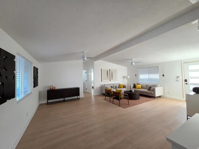 Living area with healthy amount of natural light, light wood-type flooring, beam ceiling, and ceiling fan