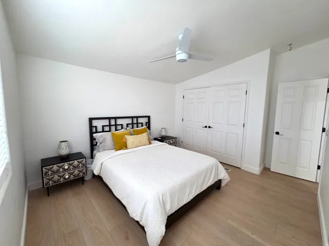 Bedroom featuring light wood-style flooring, vaulted ceiling, a closet, and ceiling fan