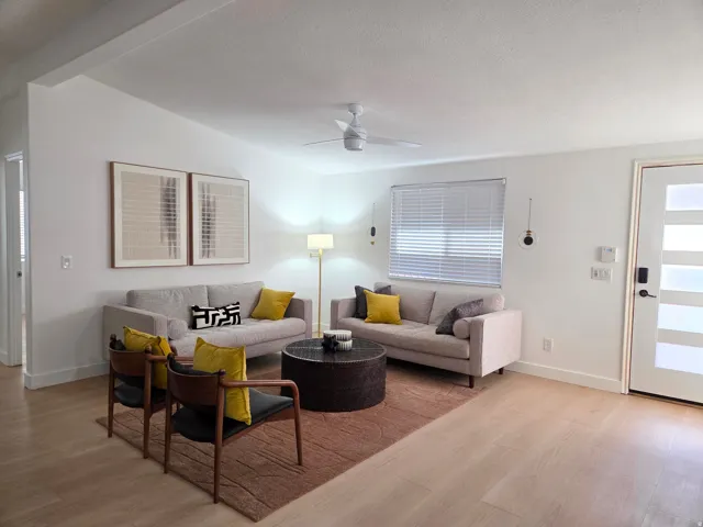 Living area featuring light wood finished floors, a ceiling fan, and a textured ceiling