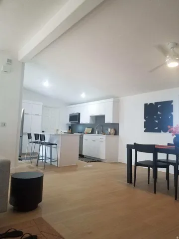 Kitchen with white cabinets, light wood finished floors, light countertops, a ceiling fan, and vaulted ceiling