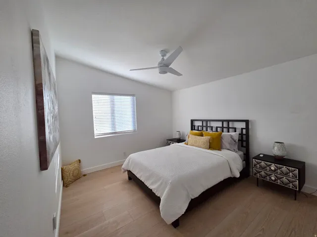 Bedroom with light wood-style flooring, ceiling fan, and lofted ceiling