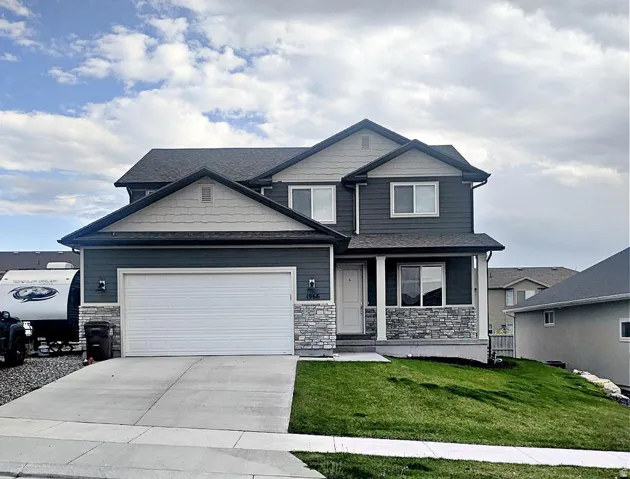 Craftsman inspired home with stone siding, a front yard, covered porch, and driveway