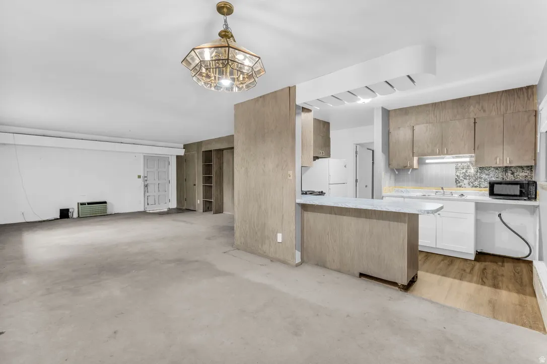 Kitchen featuring wood-finish cabinetry, white appliances, and a breakfast bar .
