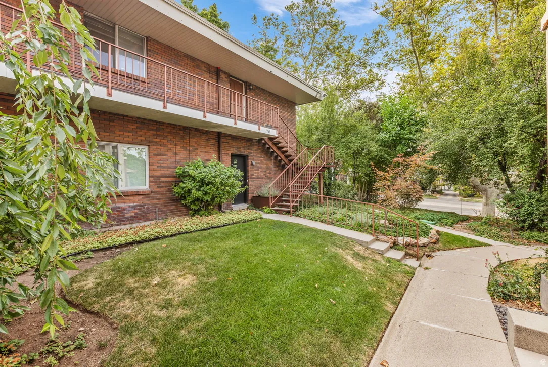 Brick exterior with mature landscaping and expansive lawn featuring manicured grounds, concrete walkway, and established shad trees.