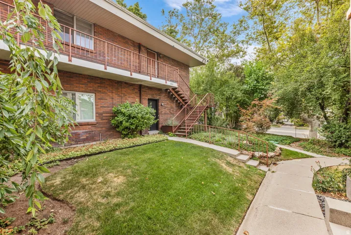 Brick exterior with mature landscaping and expansive lawn featuring manicured grounds, concrete walkway, and established shad trees.