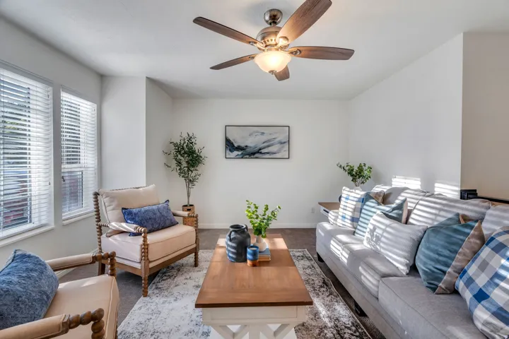 Carpeted formal living area featuring baseboards and ceiling fan