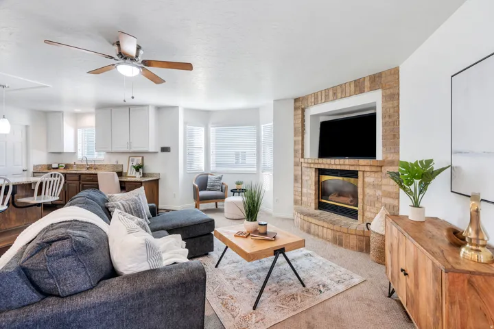 Carpeted living room with a ceiling fan, a textured ceiling, and a fireplace