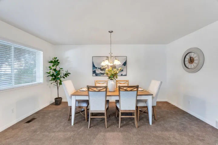 Carpeted dining space with hanging lights and baseboards