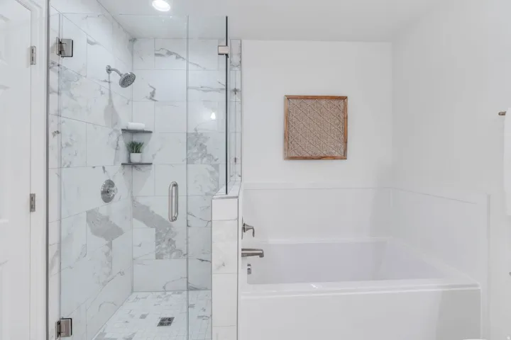 Primary Suite Bathroom featuring a marble finish shower and a bath