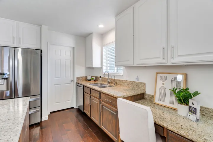 Dual tone kitchen with stainless steel appliances, light stone countertops, dark wood flooring, recessed lighting, and two tone cabinets